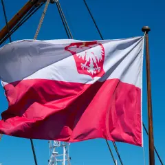 Flaga na statku powiewa na wietrze. Biało-czerwona flaga z orłem dumnie reprezentuje Polskę na morzu.