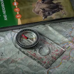 Kompas żeglarski leży na mapie Bieszczad, gotowy do wyznaczania trasy.