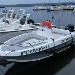 Łodzie motorowe cumujące przy pomoście, gotowe na czarter na Zalewie Sulejowskim. Jedna z nich ma napis "BEZPATENTÓWKA".
