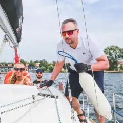 Ludzie na żaglówce cieszą się pięknymi **drogami wodnymi w Polsce**. Słońce, woda i przyjaciele to idealne połączenie.