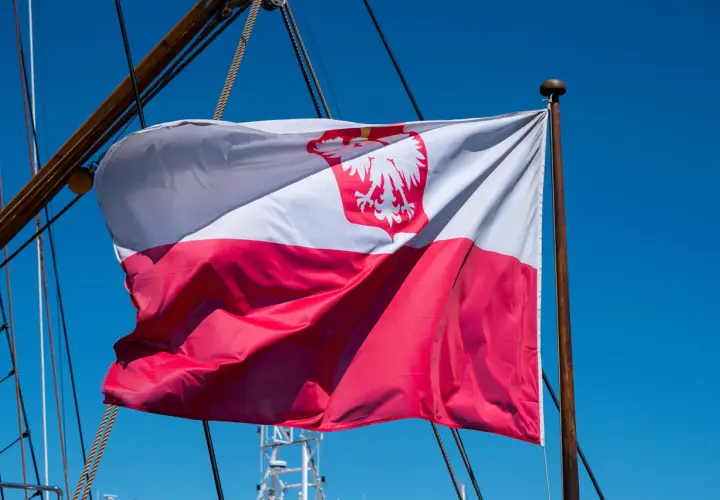 Flaga na statku powiewa na wietrze. Biało-czerwona flaga z orłem dumnie reprezentuje Polskę na morzu.