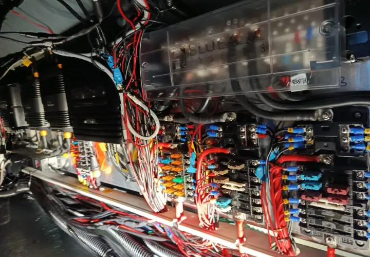 Skomplikowana instalacja elektryczna na jachcie, z widocznymi bezpiecznikami, przewodami i skrzynką "Blue Sea Systems".