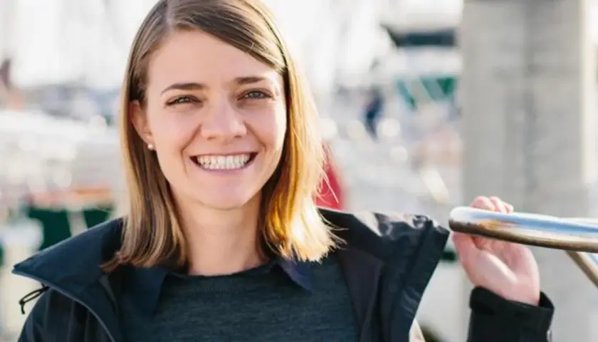 Uśmiechnięta Jessica Watson, która przetrwała sztorm, na tle łodzi.