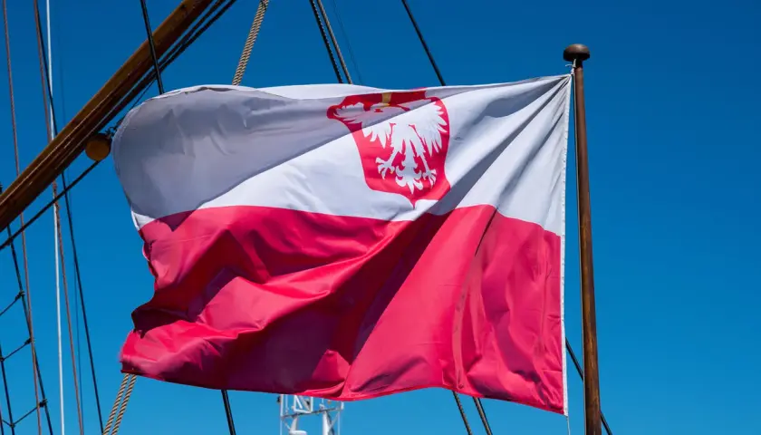 Flaga na statku powiewa na wietrze. Biało-czerwona flaga z orłem dumnie reprezentuje Polskę na morzu.