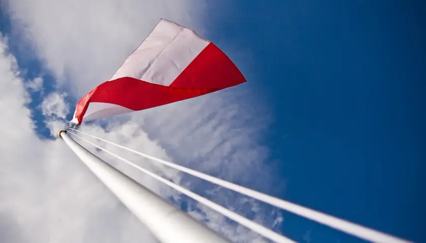 Biało-czerwona flaga powiewa na tle błękitnego nieba. Czy można wywiesić flagę innego kraju? To pytanie zadaje sobie wielu.