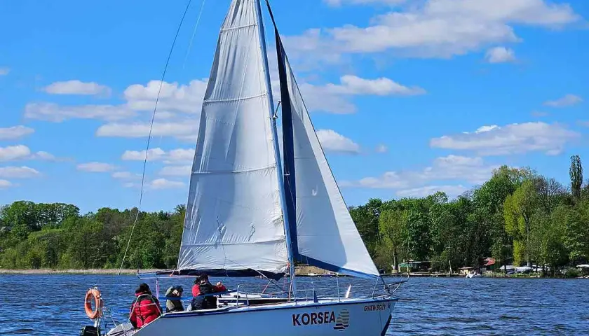 Żaglówka "KORSEA" płynie po jeziorze, osiągając dobrą morska jednostka prędkości.