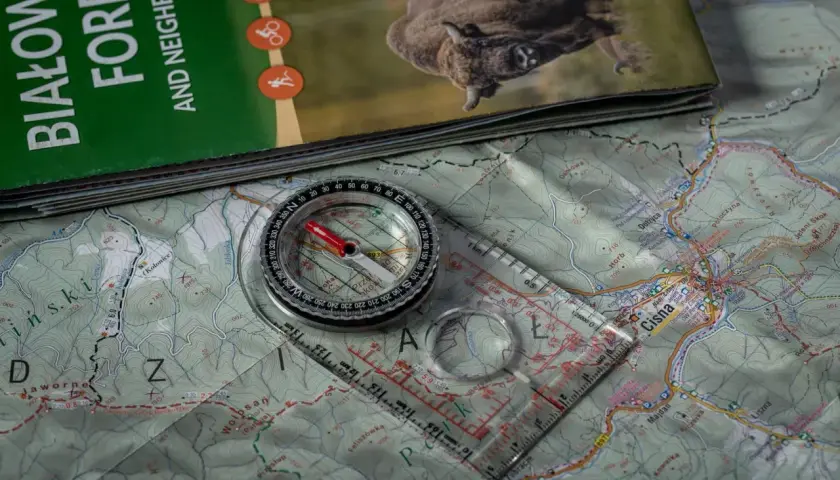 Kompas żeglarski leży na mapie Bieszczad, gotowy do wyznaczania trasy.