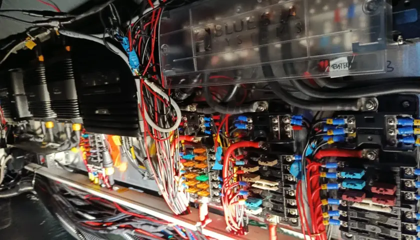 Skomplikowana instalacja elektryczna na jachcie, z widocznymi bezpiecznikami, przewodami i skrzynką "Blue Sea Systems".