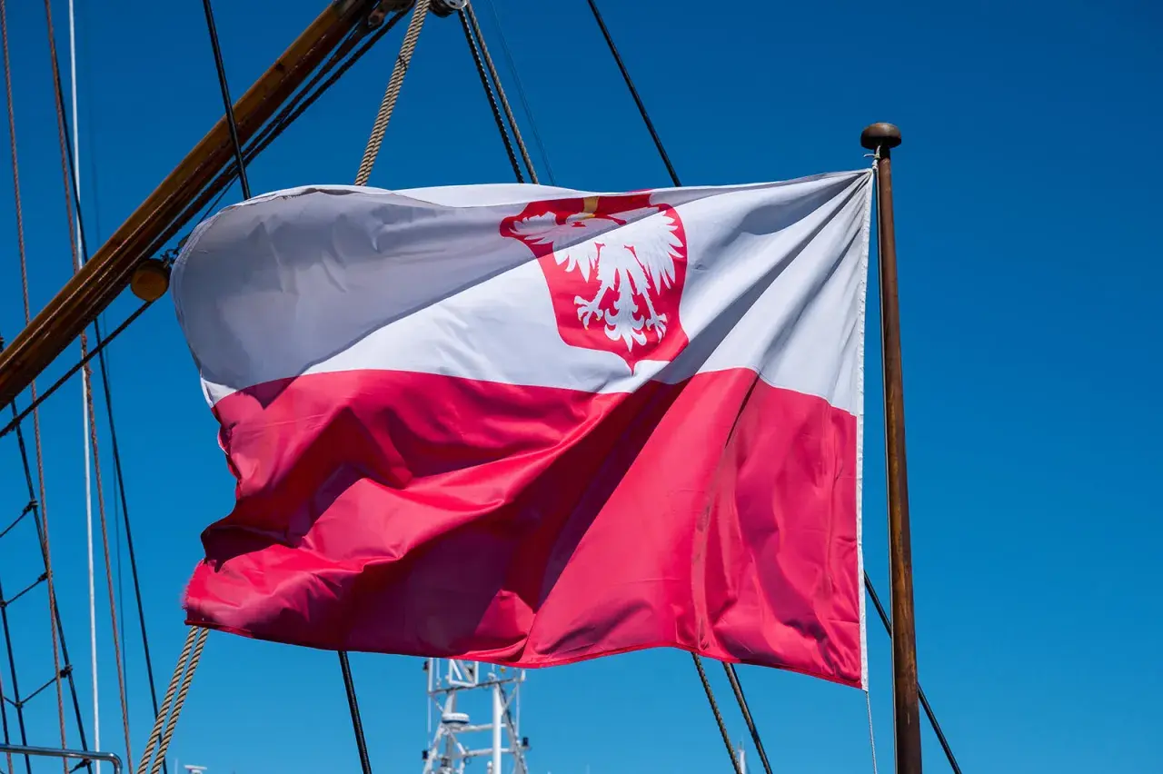 Flaga na statku powiewa na wietrze. Biało-czerwona flaga z orłem dumnie reprezentuje Polskę na morzu.