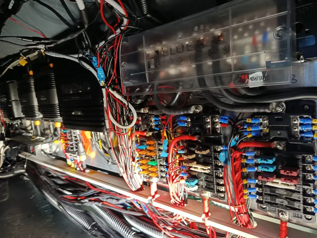 Skomplikowana instalacja elektryczna na jachcie, z widocznymi bezpiecznikami, przewodami i skrzynką "Blue Sea Systems".