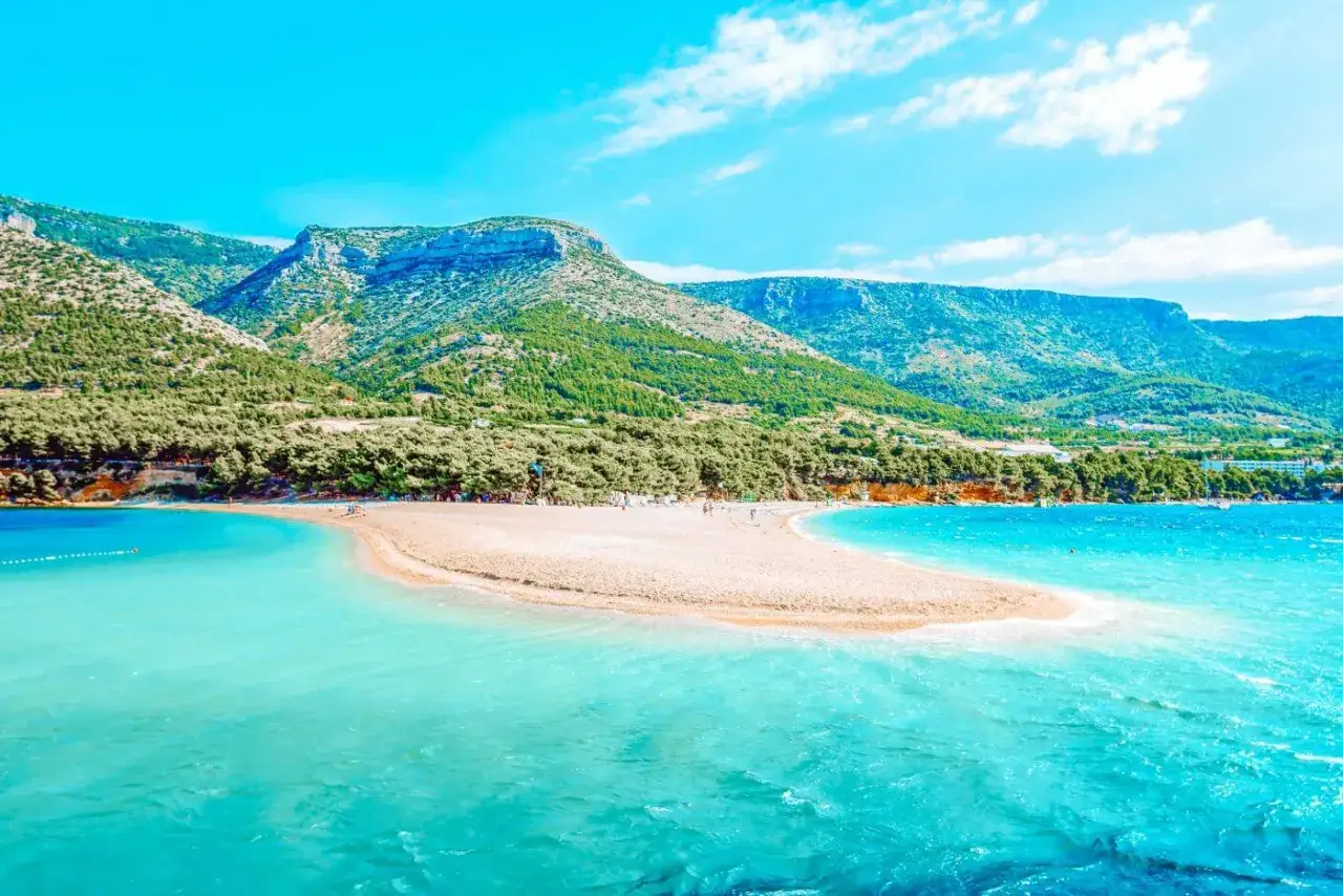 Piękna plaża Zlatni Rat, idealna na jednodniowe rejsy ze Splitu. Turkusowe morze i zielone wzg&oacute;rza.